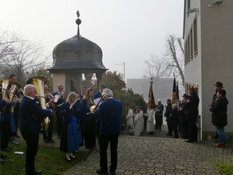 Eine Menschengruppe steht vor dem Kriegerdenkmal.